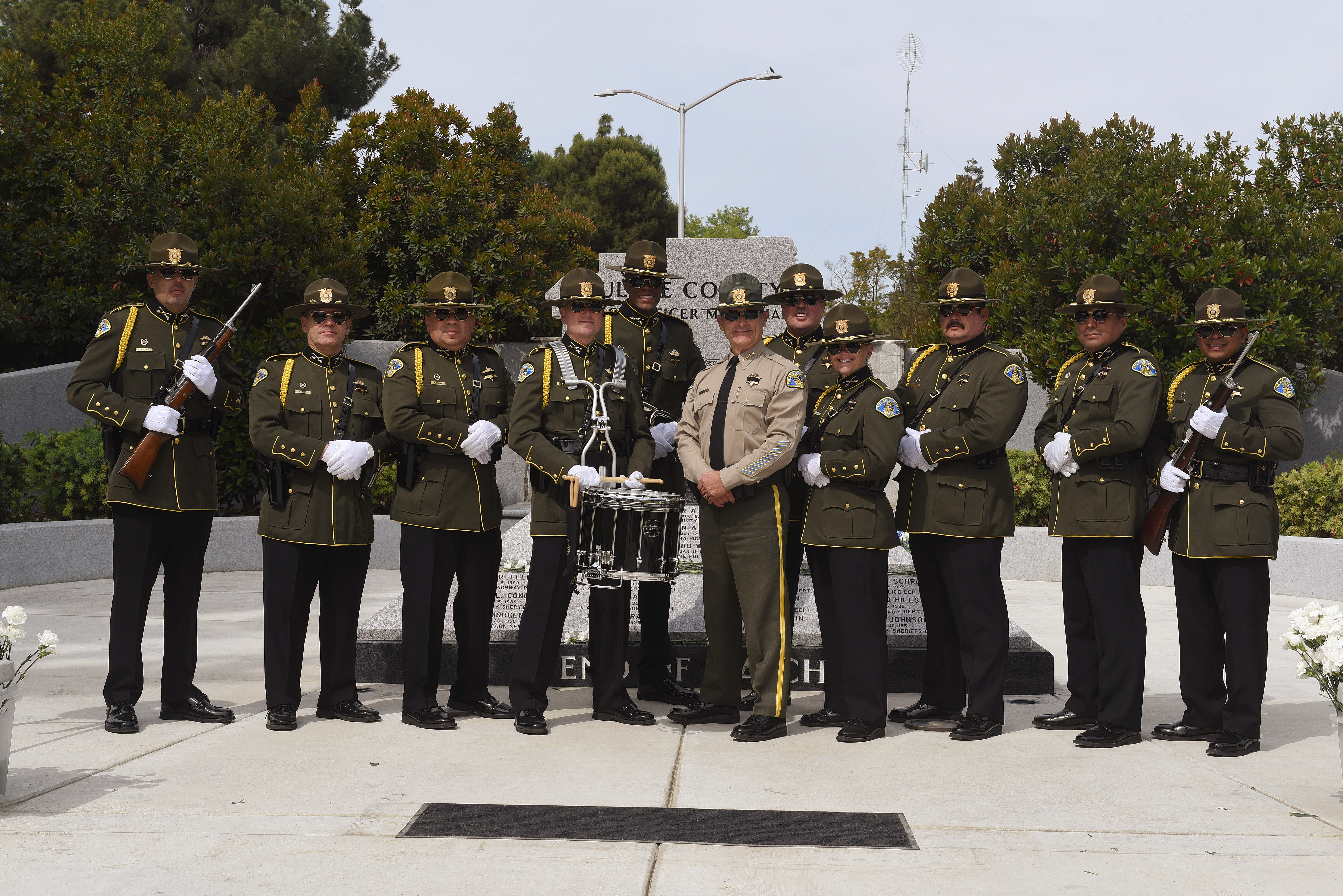 Eleven members of the Sheriff's Honor Guard stand in a line in front of the Peace Officer Memorial and pose for the portrait.