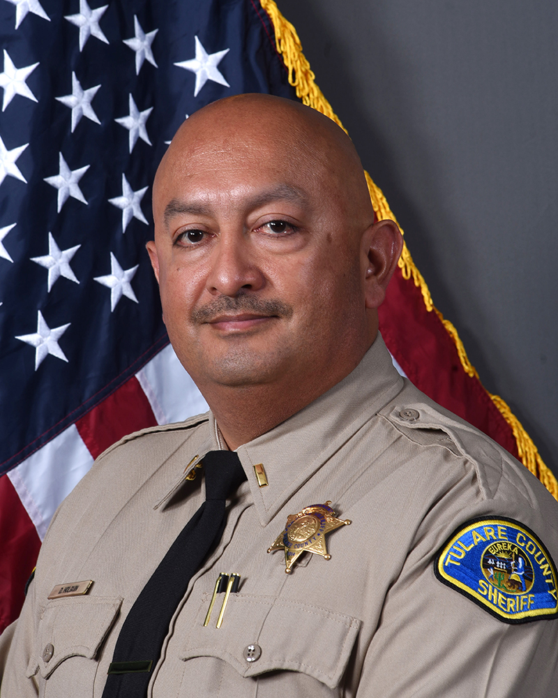 A portrait of Lt. Demecio Holguin in uniform in front of American Flag
