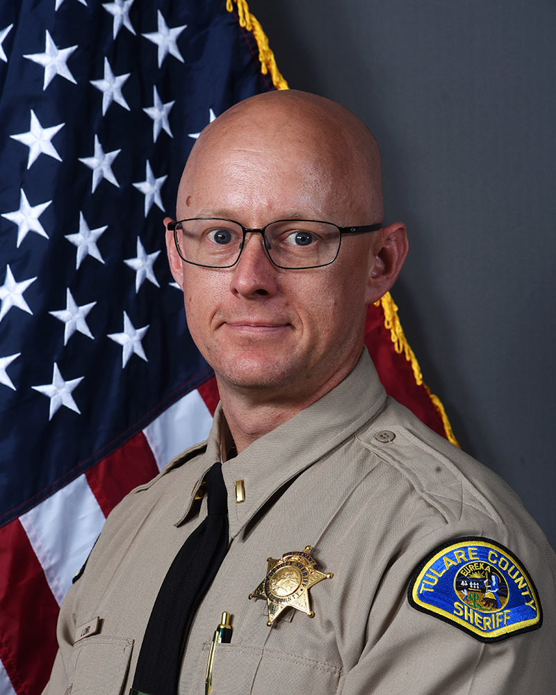 A head and shoulders portrait of Lt. Josh Lowry in uniform in front of the American Flag. 
