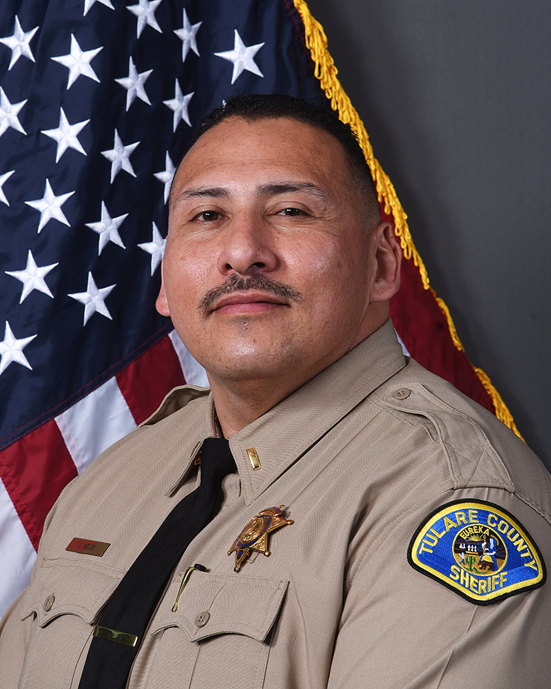 A head and shoulders portrait of Lt. Jerry Neves in uniform in front of an American Flag.