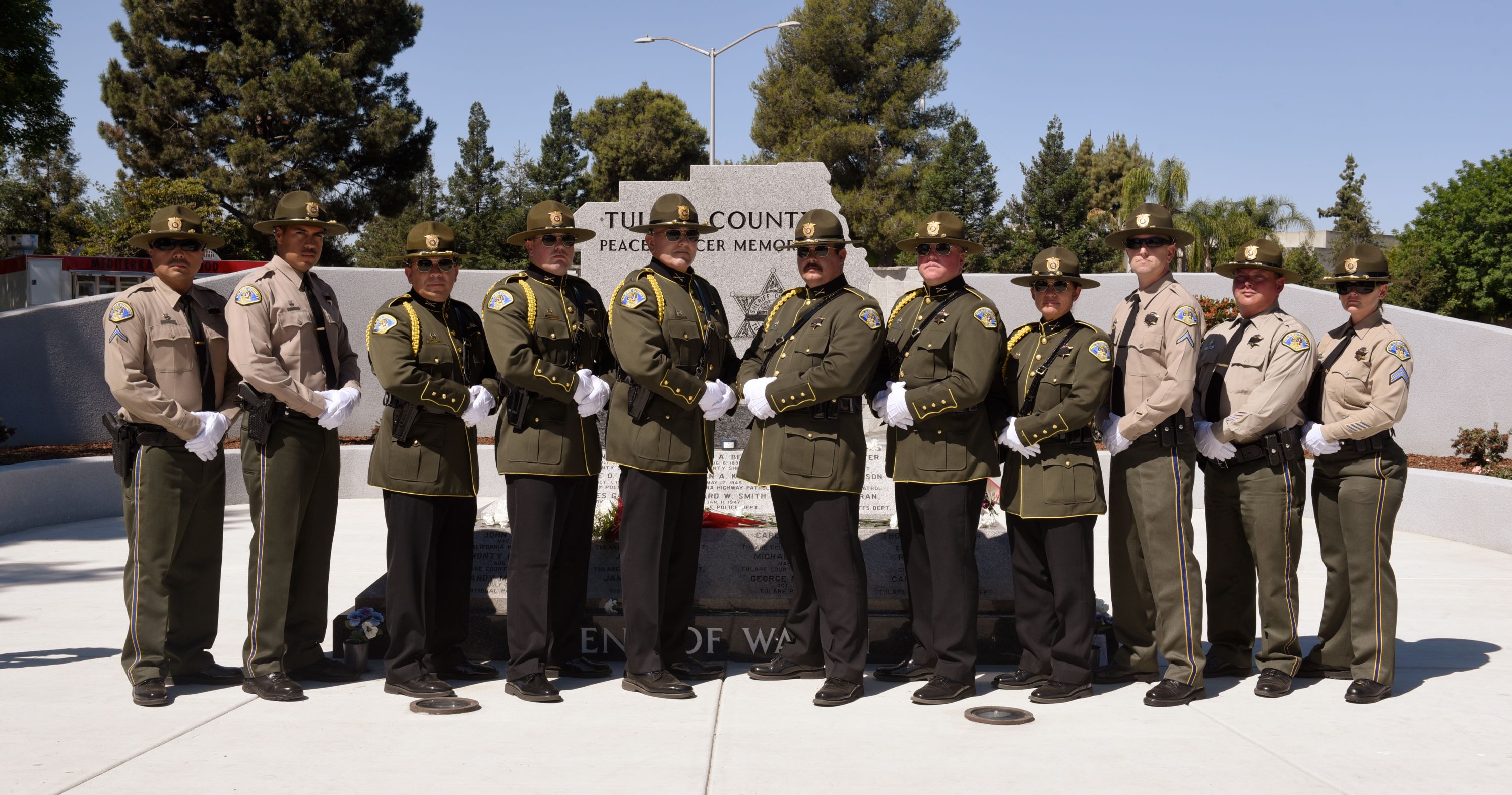 Eleven members of the Sheriff's Honor Guard stand in a line in front of the Peace Officer Memorial and pose for the portrait.