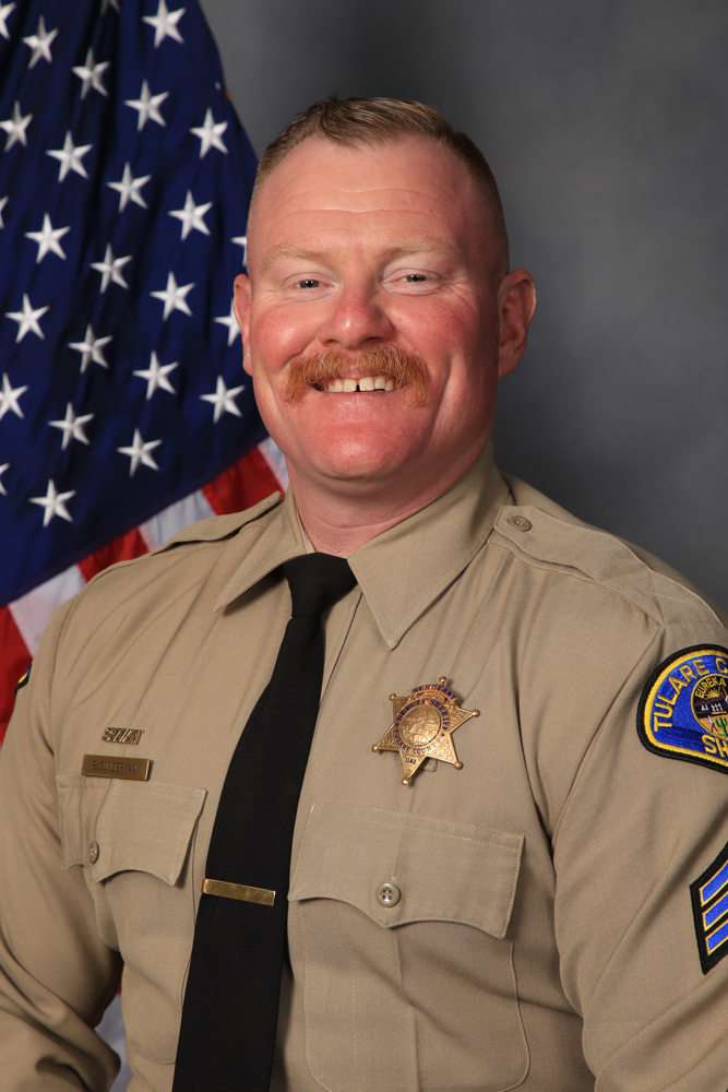 A head and shoulders portrait of Lt. Randall Gunderman in uniform in front of an American Flag.